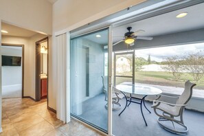 A modern interior with a glass door leading to a patio area with a table and chairs, a ceiling fan, and a view of the outdoors. - Merrimack Place (Davenport)