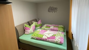 Une chambre à coucher avec un lit, des oreillers, un élément de décoration murale et une fenêtre avec des rideaux.