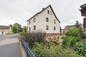 A two-story residential building with a symmetrical facade, a brick base, and a pitched roof. - Holiday Apartment "Auszeit" with Private Terrace, Garden, and Wi-Fi (Bad Liebenwerda)