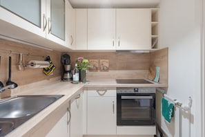 A modern kitchen with a dishwasher, oven, and a coffee machine. - Holiday Apartment "Auszeit" with Private Terrace, Garden, and Wi-Fi (Bad Liebenwerda)