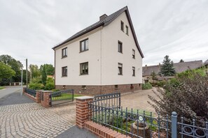 A two-story residential building with a brick base and a white upper section. - Holiday Apartment "Auszeit" with Private Terrace, Garden, and Wi-Fi (Bad Liebenwerda)