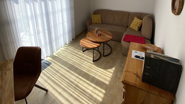 Un salon comprenant un canapé, une table basse, un fauteuil et un meuble en bois.