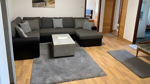 Ein modernes Wohnzimmer mit einem Ecksofa, einem Couchtisch und einem Teppich.
