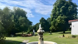 Ein Garten mit Springbrunnen, Blumentöpfen und einem Weg.