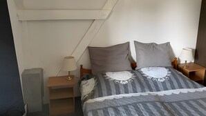 Ein Schlafzimmer mit einem Bett, zwei Nachttischen, einer Lampe auf jedem Tisch und einem Wandregal.