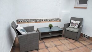A small patio area with wicker furniture, a tiled floor, and a decorative tile border. - Casa rural La Bandolera (Grazalema)