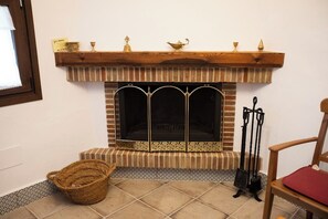 Una chimenea con repisa, una cesta y una silla.