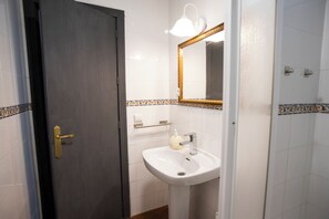 A bathroom with a white sink, a mirror with a gold frame, and a door with a gold handle.