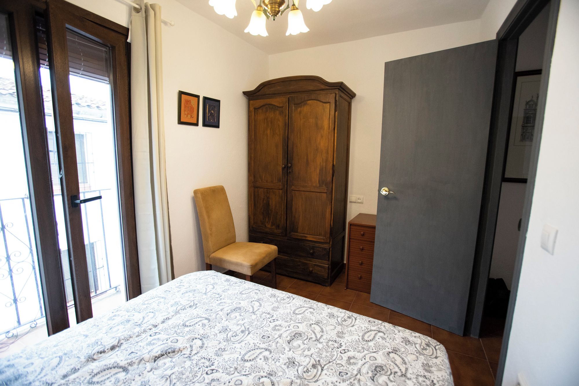Een slaapkamer met een bed, een kledingkast, een stoel en een deur.
