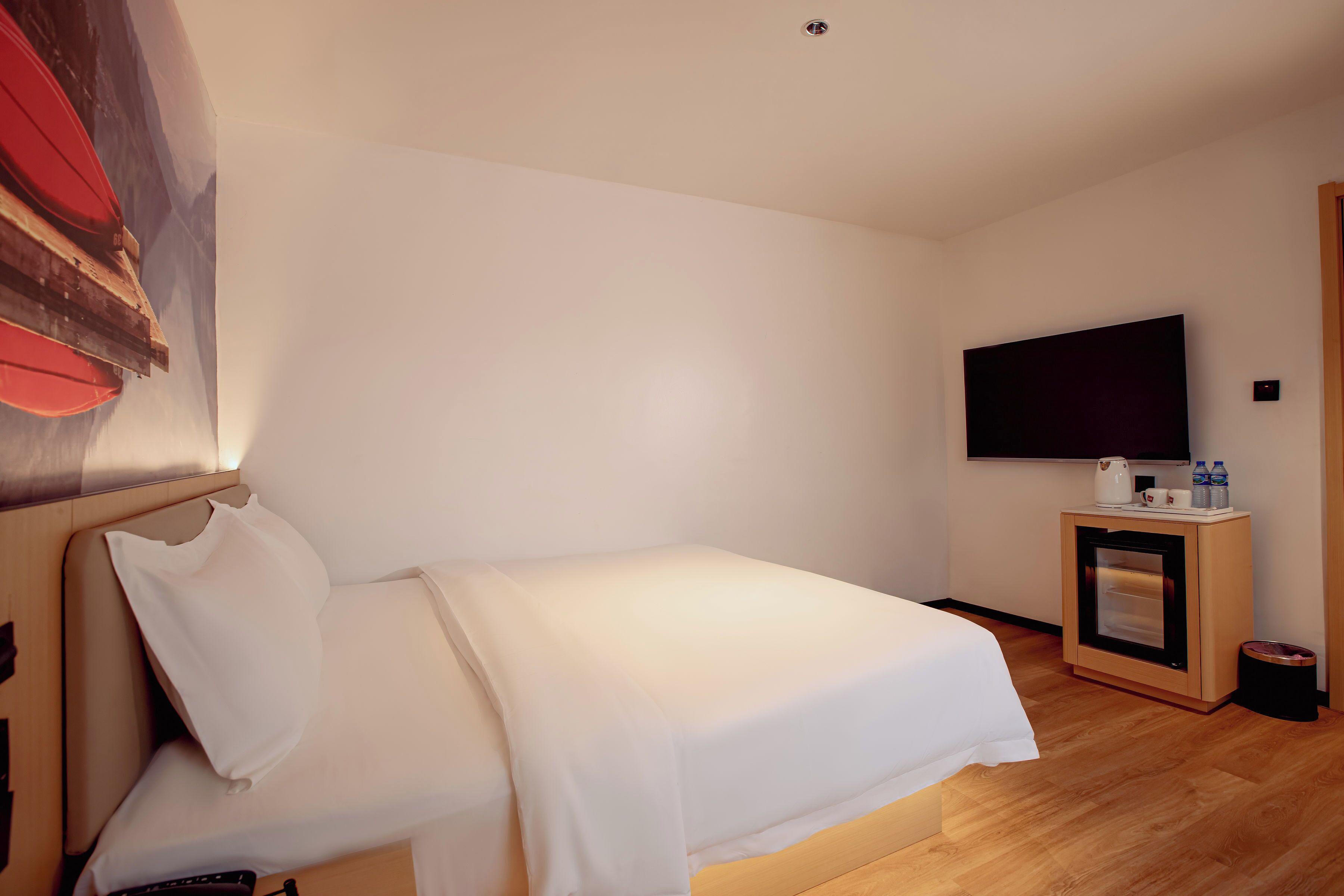 A hotel room with a bed, a television mounted on the wall, and a small cabinet with a microwave.
