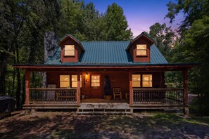 A cabin with a porch, two windows on the front, and a door. - Cabin Fever by Beyond Expectations: 5-Star Cabin w/ Hot Tub, FirePit & Game Room (Gatlinburg)