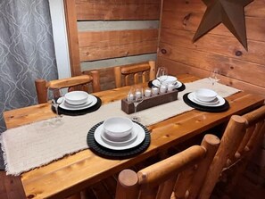 Ett matbord i trä med vita tallrikar, tallrikar med svarta kanter och klara glas, och en trästol på varje sida.