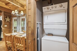 Un interior de madera con zona de comedor, lavadora y refrigerador.