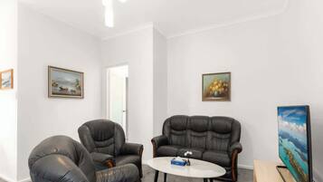 A room with two leather sofas, a round coffee table, and a painting on the wall.
