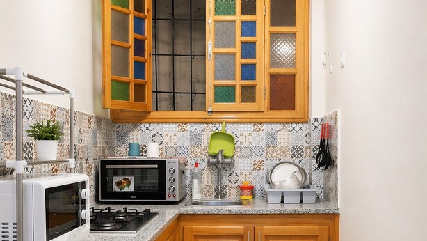 A compact kitchen with a microwave, oven, sink, and wooden cabinets. - "Dar Mina" in the Heart of Fes Medina (fes)