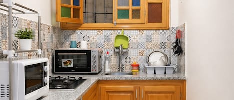 A compact kitchen with a microwave, oven, sink, and wooden cabinets.
