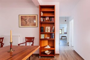 A dining area with a wooden table, chairs, a bookshelf, and a framed map on the wall.