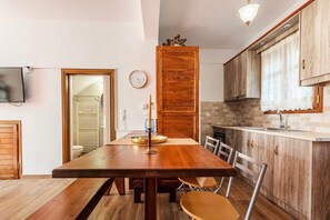 A dining area with a wooden table and chairs, a clock on the wall, and wooden cabinets.