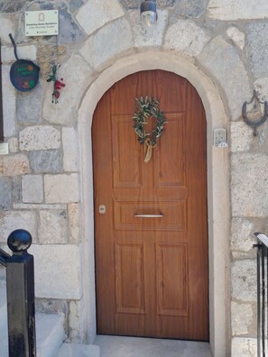 A stone facade with a wooden door, a sign above it, and a small light fixture above the door.