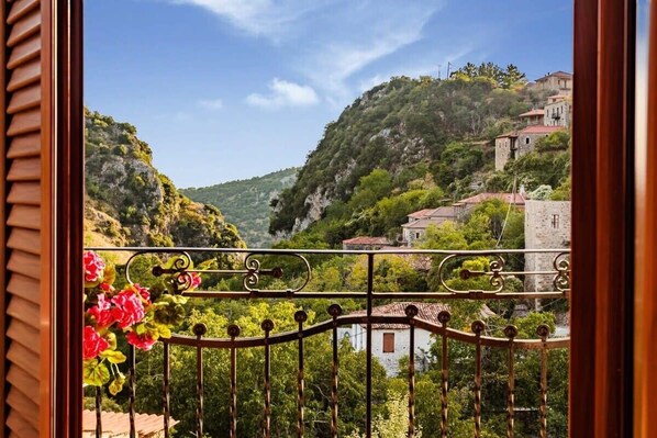 A balcony with a wrought iron railing and a view of a hillside with buildings.
