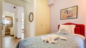 Ein Schlafzimmer mit einem Bett, einer roten Kopfteil, einem großen Kleiderschrank und einem gerahmten Kunstwerk an der Wand.
