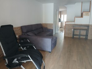 A living room with a sofa, a black office chair, and a small table.