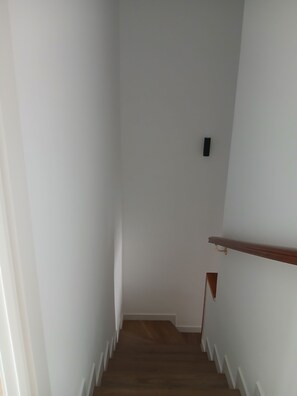 A narrow staircase with wooden steps and white walls.