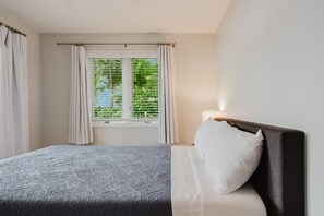 A bedroom with a bed, a window with curtains, and a bedside lamp. - Wonder Lake Extended-Stay Furnished 30-Day+ Waterfront Estate (Wonder Lake)