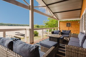 A covered outdoor seating area with wicker furniture and a view of a lake. - Wonder Lake Extended-Stay Furnished 30-Day+ Waterfront Estate (Wonder Lake)