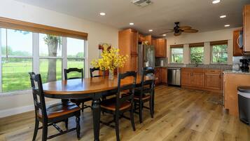 A spacious kitchen with wooden cabinets, a stainless steel refrigerator, and a dining table with chairs.