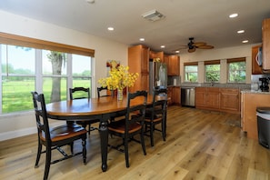 A spacious kitchen with wooden cabinets, a stainless steel refrigerator, and a dining table with chairs. - Farm Retreat in Williston, Near Gainesville & Ocala (Williston)