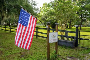 An American flag on a flagpole in a grassy area with a wooden fence and a sign for Little Ridge Ranch Vacation Rental Homes.