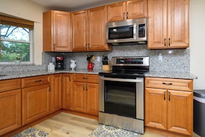 A kitchen with wooden cabinets, a stainless steel oven, and a microwave. - Farm Retreat in Williston, Near Gainesville & Ocala (Williston)