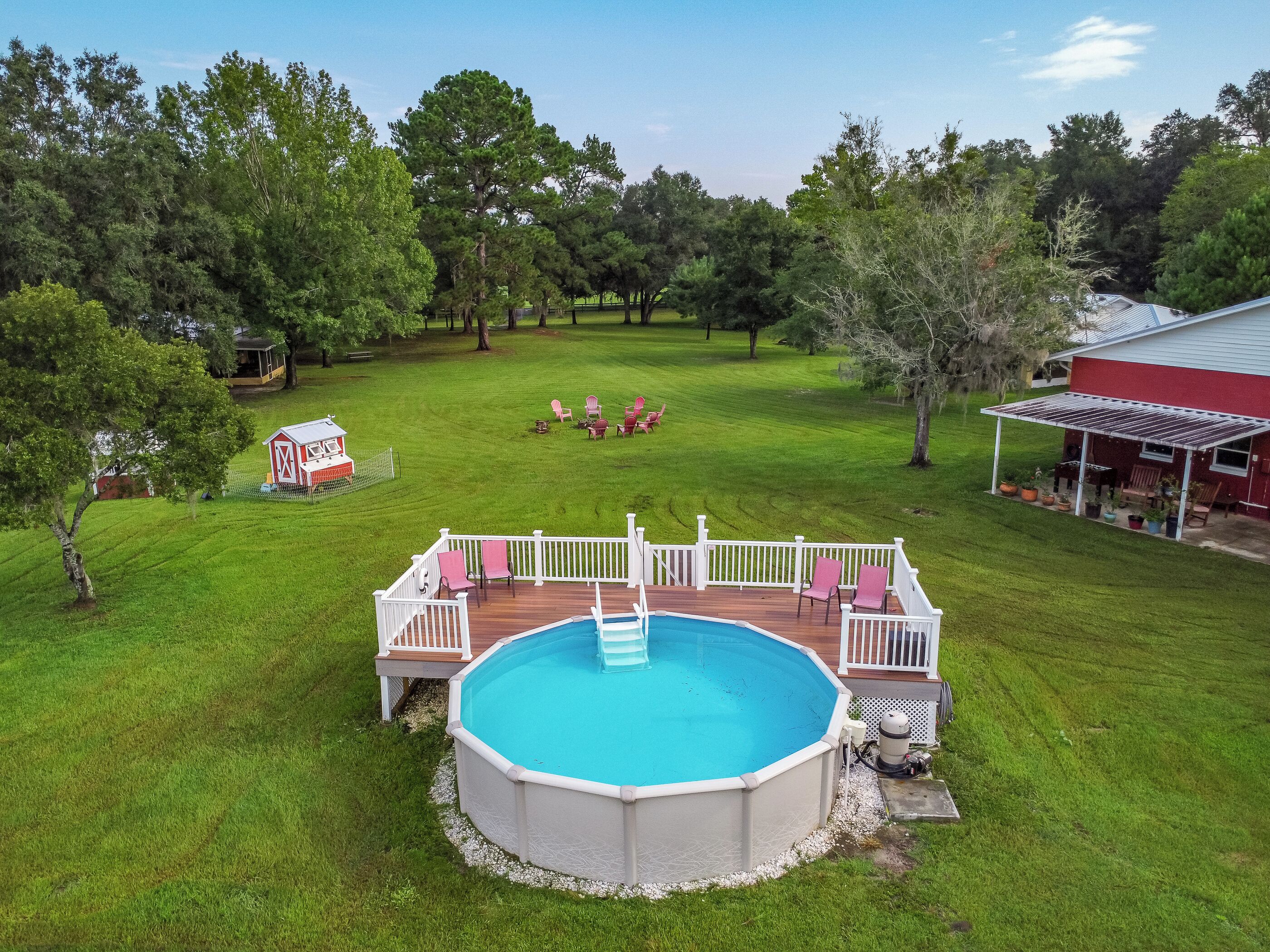 A backyard with a swimming pool, deck, and outdoor seating area.