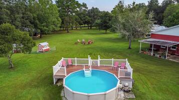 A backyard with a swimming pool, deck, and outdoor seating area.