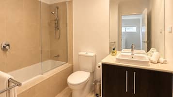 Een moderne badkamer met een douchecabine van glas, een toilet, een wastafel met spiegel en een donker houten kast.