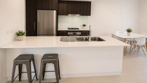Een moderne keuken met een centraal eiland, roestvrijstalen apparatuur en een eethoek met een tafel en stoelen.
