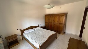 Une chambre à coucher avec un lit en bois, une table de chevet, une armoire et un luminaire suspendu.