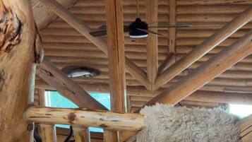 A rustic interior with wooden beams and a hanging fur rug.