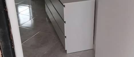 Un pasillo con un armario blanco y piso de baldosas.