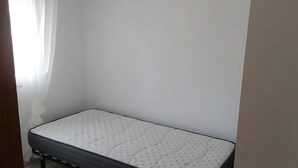 A small, single-bed room with a white mattress and a simple, unadorned wall. - Holiday Home 'Lustigmann 2' with Private Terrace, Wi-Fi and Air Conditioning (San Fulgencio)