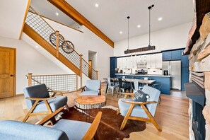A spacious living area with a wooden staircase, a dining set, and a kitchen with modern appliances.