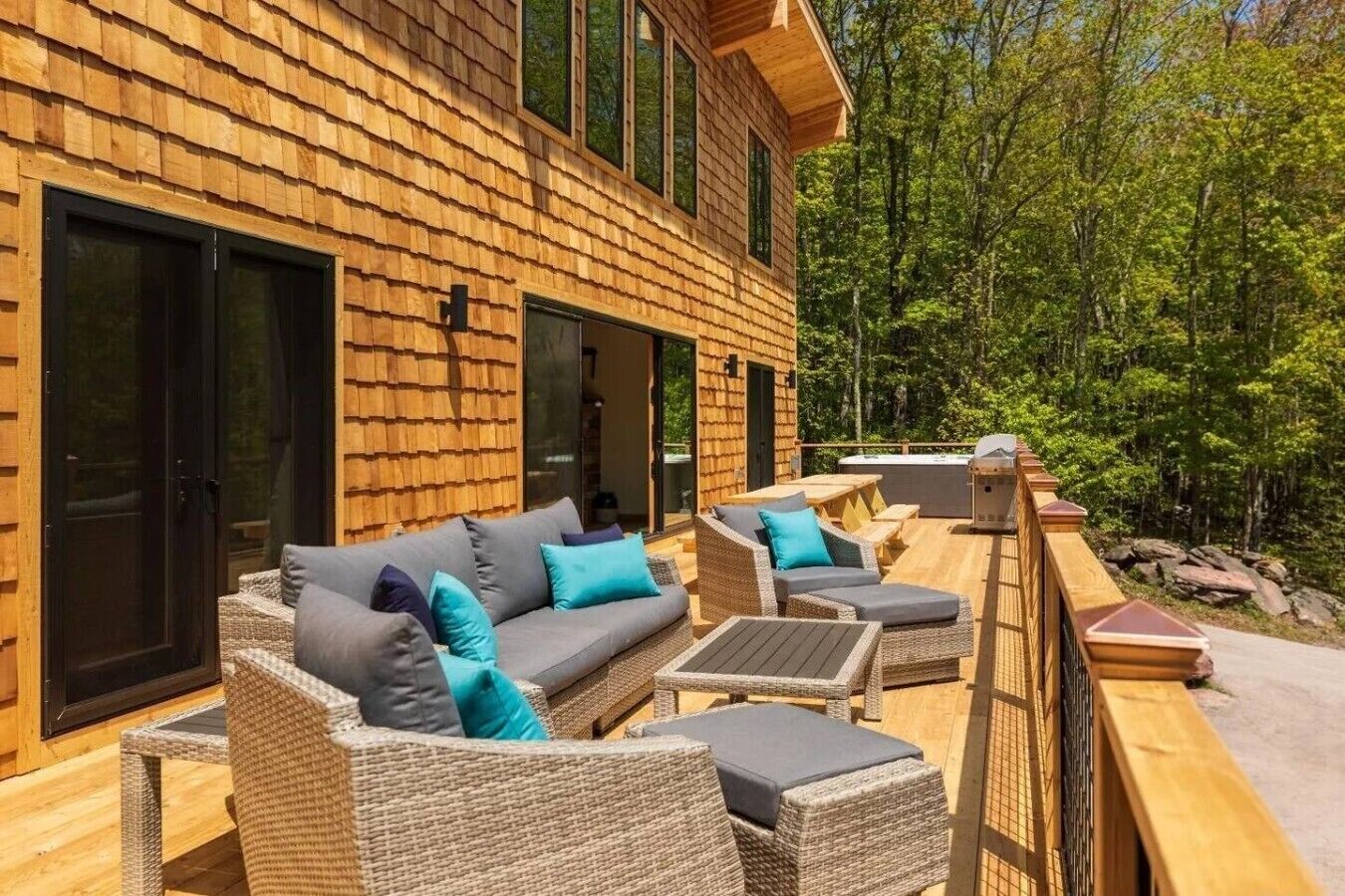 A wooden cabin with a deck furnished with outdoor seating and a hot tub.