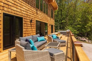 A wooden cabin with a deck furnished with outdoor seating and a hot tub.
