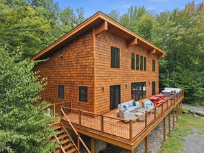 A wooden cabin with a deck, outdoor seating, and a staircase.