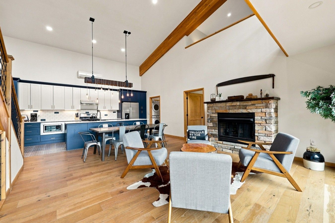 Eine moderne Küche mit blauen Schränken, ein Essbereich mit Kamin und ein Wohnzimmer mit einem Kuhfellteppich.