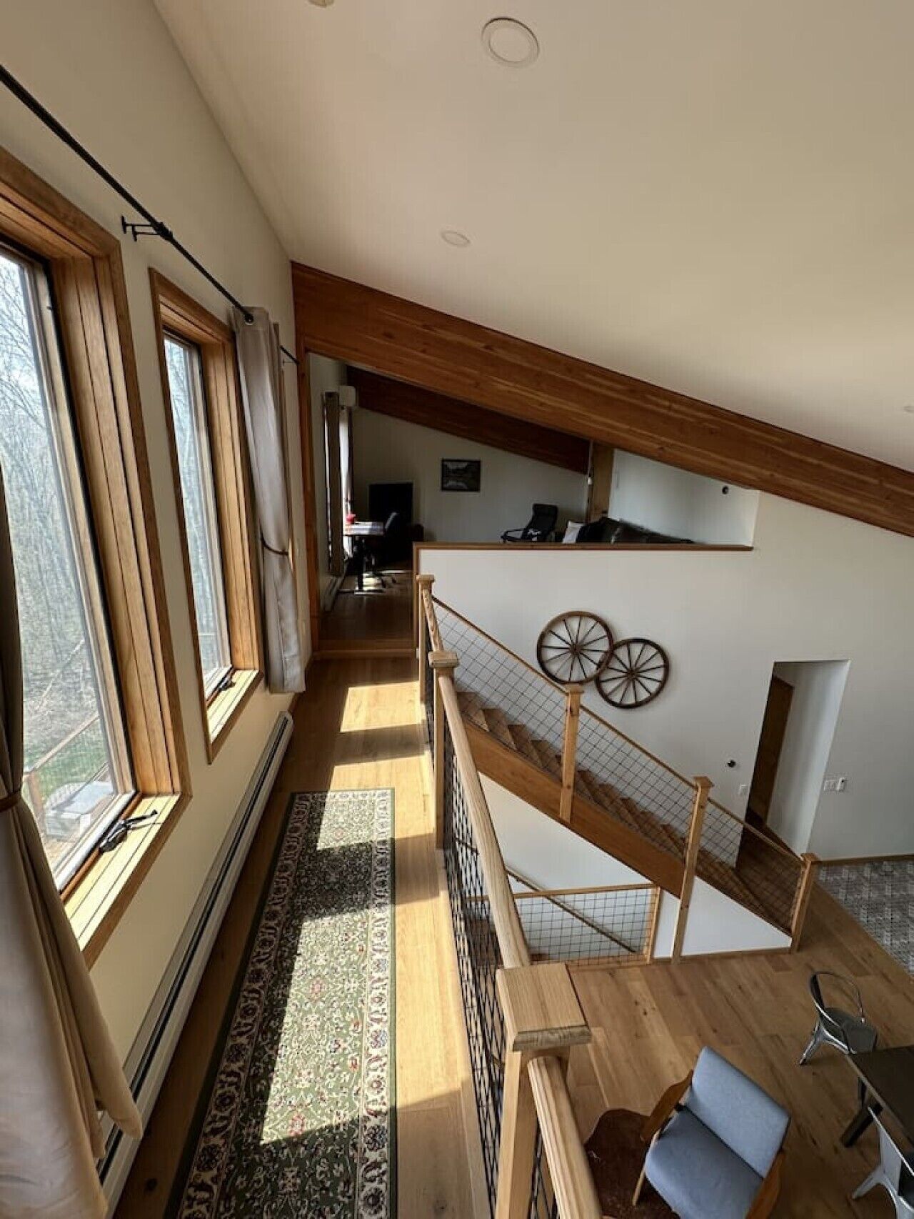 A spacious interior with a high ceiling, wooden beams, a staircase, and a view of the outdoors.