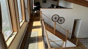 A spacious interior with a high ceiling, wooden beams, a staircase, and a view of the outdoors.