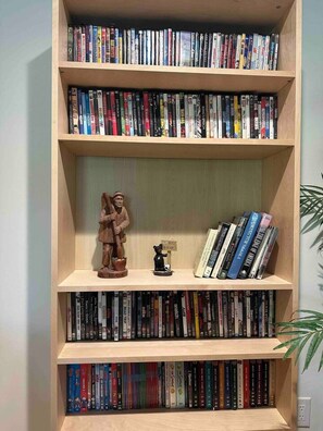 Uma estante com várias prateleiras cheias de livros, uma pequena estatueta e um vaso com planta.