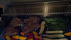 En grill med forskellige kød- og grøntsagsretter, der tilberedes.